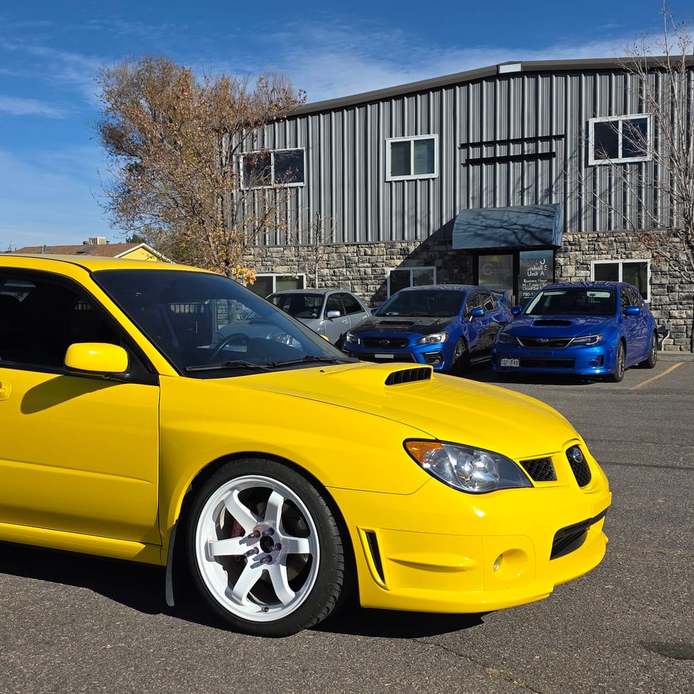 Yellow Subaru WRX outside the shop